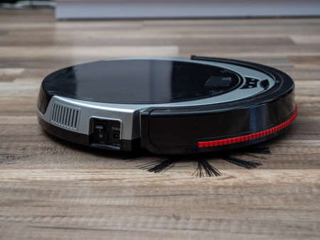 Robotic vacuum cleaner on a laminated wooden floor. Robot vacuum cleaner.の写真素材