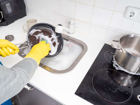 Washing dishes while cleaning the house. Kitchen cleaning. Dirty dishes.の写真素材