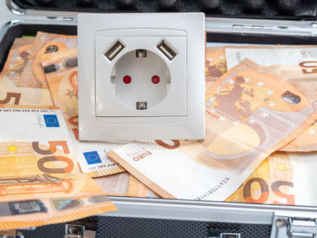 The electrical outlet is in a suitcase with money. Electricity cost and expensive energy concept.