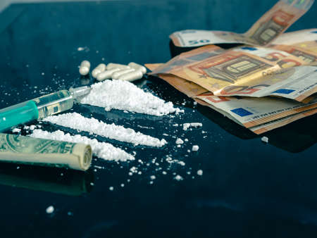 Money and drugs on a black glass table. Money, syringes and drugs.の写真素材