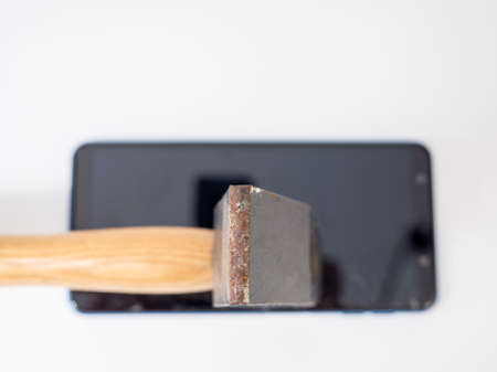 A hammer with a wooden handle breaks a smartphone.の写真素材