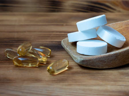 Tablets and capsules in a wooden spoon. Multivitamins and supplements from natural concept.の写真素材