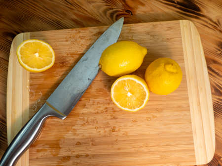Sliced lemons with a knife. Ripe lemon on a wooden board. Fresh lemons on a wooden background.の写真素材