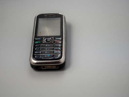 Old push button mobile phone. Broken phone. Phone on a gray background.の写真素材