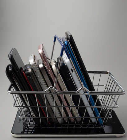 Phones of different models and generations are in the shopping cart. Smartphone on a gray...
