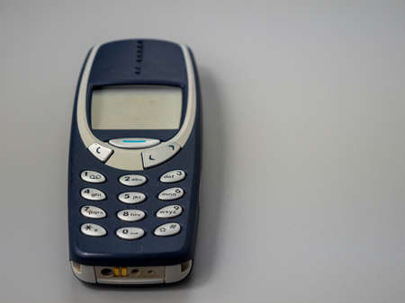Old push button mobile phone. Broken phone. Phone on a gray background.の写真素材
