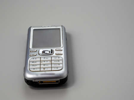 Old push button mobile phone. Broken phone. Phone on a gray background.の写真素材