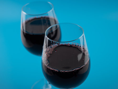 A glass of wine on a blue background. Glass goblet with wine.