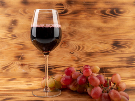 Glass of wine and grapes on a wooden background. Glass goblet with wine.の写真素材