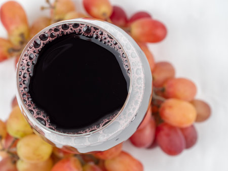 A glass of wine and grapes on a white background. Glass goblet with wine.の写真素材