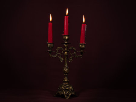 Burning red candles in a candlestick. Lighted candles in an old candlestick. Close up.の写真素材