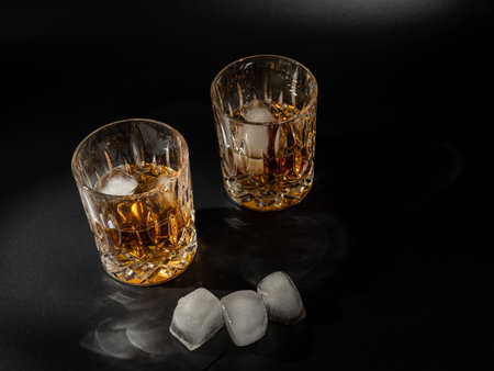 Whiskey, bourbon or cognac with ice cubes on a black background. Close up.の写真素材