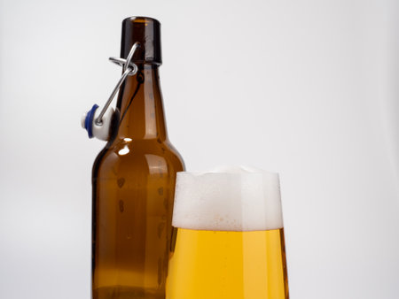 Glass and bottle of beer on a white background. Glass of light beer with foam. close up.の写真素材