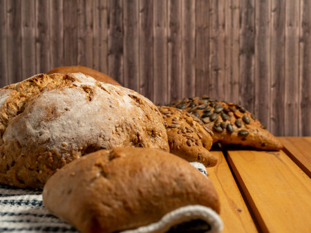 Dark bread and buns on a wooden background. Bakery products with grains. Close up.の写真素材