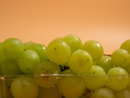 Green grapes. Ripe grapes on an orange background. Close up.