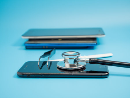 Smartphone and medical stethoscope. Smartphone diagnostics and repair. Medical stethoscope on smartphone blue background.の写真素材