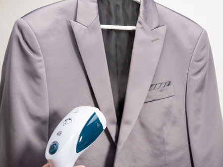 In hand Steamer for clothes. The suit is ironed with a portable iron. Iron for ironing clothes.の写真素材