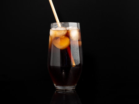 Glass of cola with ice on a black background. Close up.の写真素材