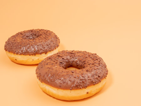 Chocolate donut with chocolate chips on an orange background. close up.の写真素材