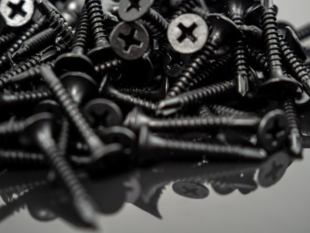 Black screws for drywall on a black background. Close up.