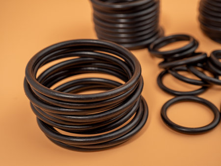 Hydraulic and pneumatic o-rings in black in different sizes on an orange background. Rubber gaskets...