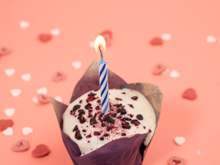 Muffin with a candle on a pink background. Holiday muffins. Close up.