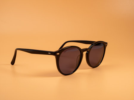 Stylish sunglasses. Sunglasses in a dark frame on an orange background. Close up.