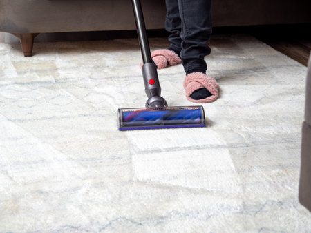 A woman vacuums the room with a modern vacuum cleaner. Cleaning of the apartment. Close up.の写真素材