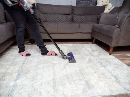 A woman vacuums the room with a modern vacuum cleaner. Cleaning of the apartment. Close up.の写真素材