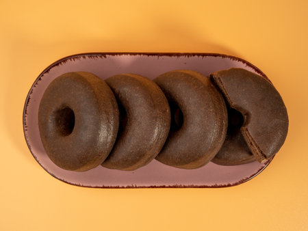 Fresh dark vegetarian donut on a plate on an orange background. Close up.の写真素材