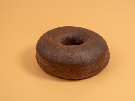 Fresh dark vegetarian donut on orange background. Close up.の写真素材