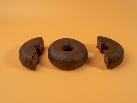 Fresh dark vegetarian donut on orange background. Close up.の写真素材