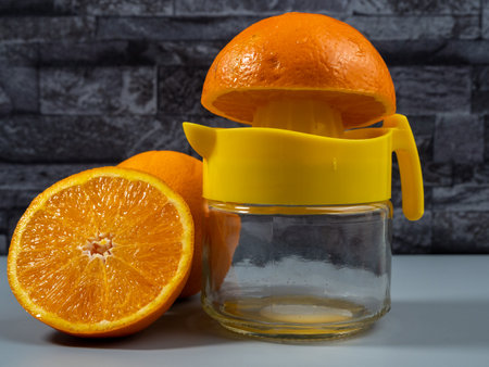 Orange juicer with ripe oranges. Fresh juice. Gray background.の写真素材
