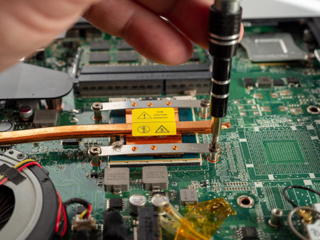 The master repairs a broken laptop with a screwdriver. Specialist and old broken laptop.の写真素材