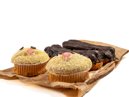 Muffin and chocolate eclairs isolated on white background. Delicious sweets. Close up.
