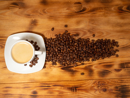 Cup of coffee and roasted coffee beans on a wooden background. Cup of coffee close-up.の写真素材