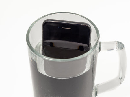 Smartphone in a glass of water. The smartphone fell into the water. Mobile phone in the water on a white background.の写真素材
