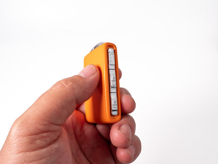 Modern wireless orange ignition key in hand on a white background. Wireless key to start the engine....