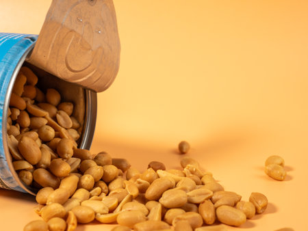 Roasted peanuts in an open jar on orange. Peanuts close up.の写真素材