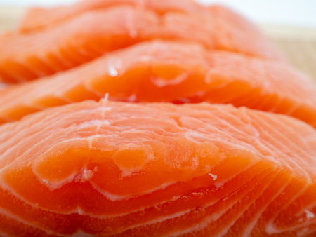 Salmon fillet on a wooden cutting board. Red fish fillet close-up on a white background. Selective focus.の写真素材