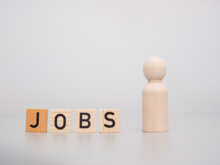 Wooden figures. The word JOBS and wooden figures on a gray background. Job search concept.の写真素材