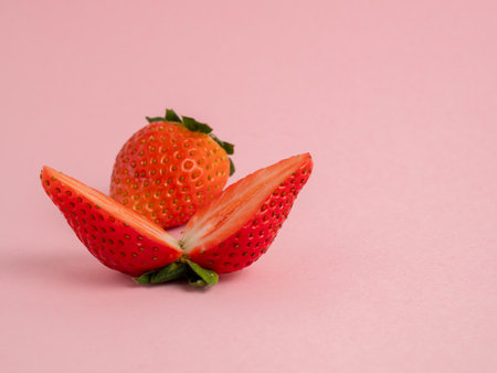 Strawberries cut in half and whole on a pink background. Strawberries close up.の写真素材