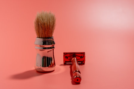 Metal razor and pen brush on a pink background. Razor close-up.