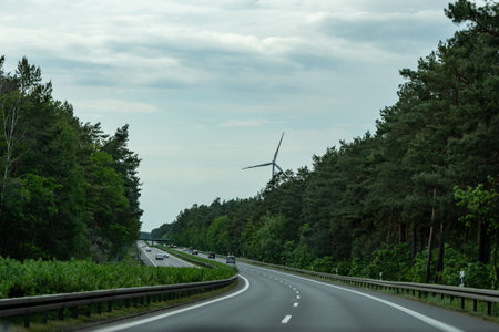 Germany, May 17, 2024. A road with a windmill in the distance. The road is empty and the sky is cloudyのeditorial素材