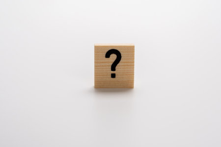 A wooden block with a question mark on it. The block is placed on a white surface. Concept of...
