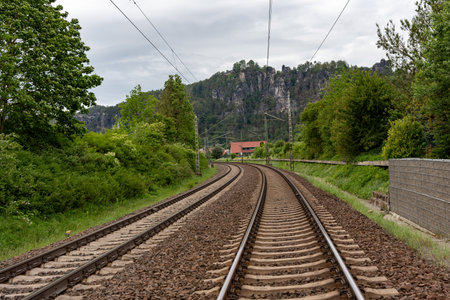 A train track with a mountain in the background. The train is not moving. The train tracks are old and wornの写真素材