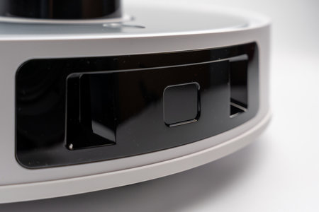 White and black robot with a black button on the side. Robot vacuum cleaner on a white background.