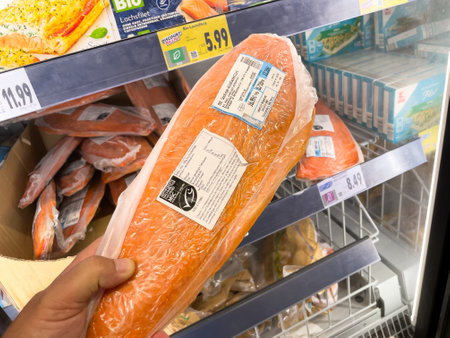 In a store, a man holds a piece of fish in a plastic bag. The price is indicated on the fish.のeditorial素材