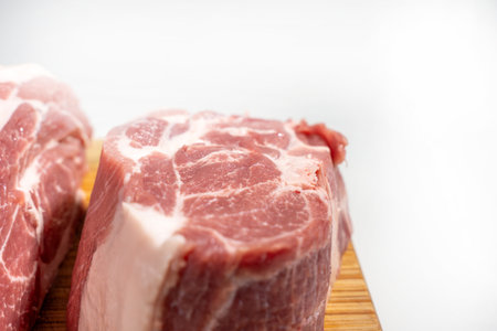 A piece of meat is on a wooden cutting board. The meat is cut into a wedge shape Pork meat isolated on a white background.の写真素材