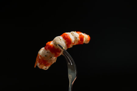 Surimi in the form of shrimp on a black background. Surimi on a fork.の写真素材